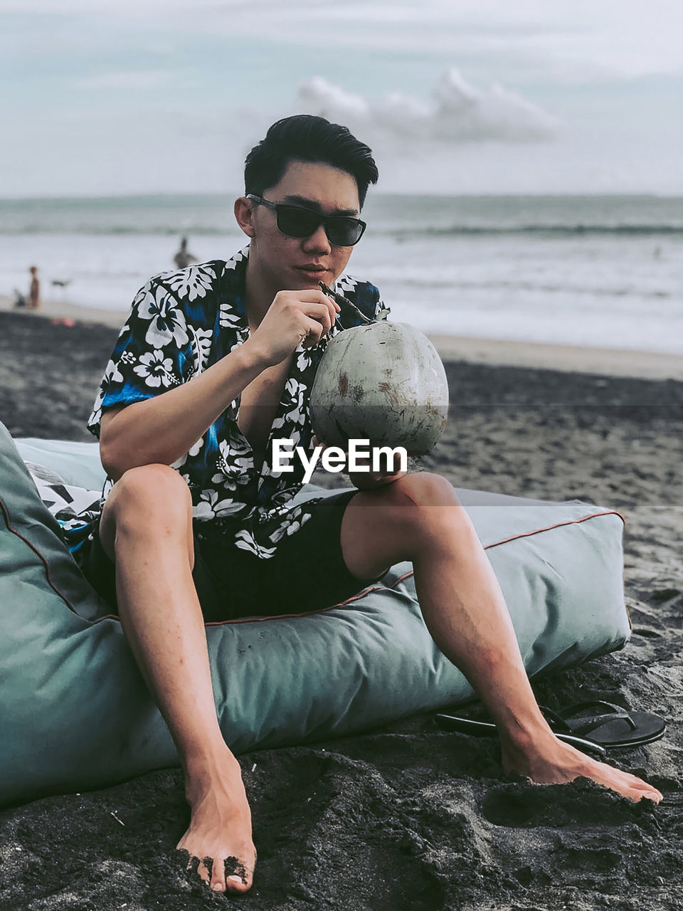 Full length of man drinking coconut water at beach