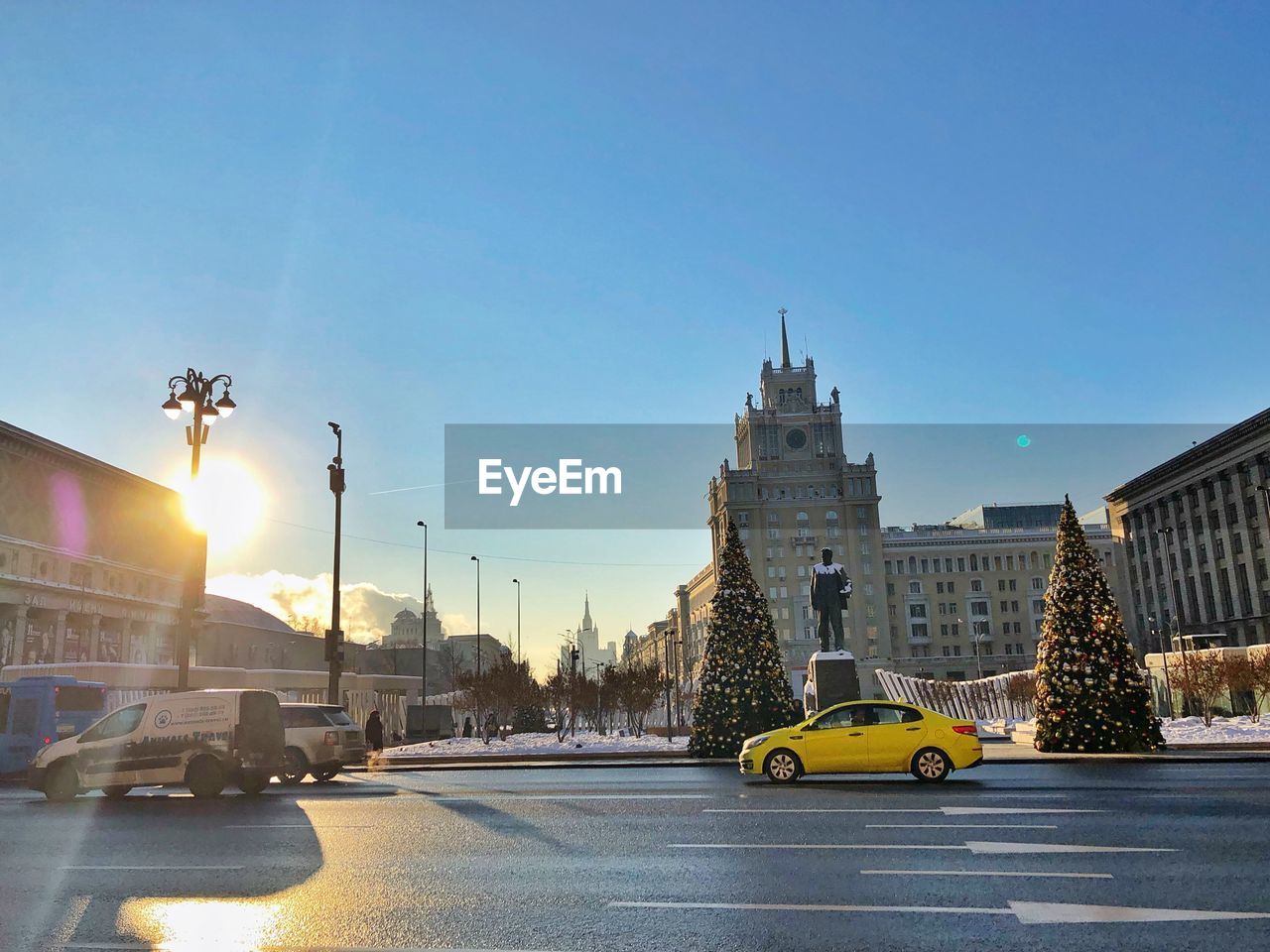 CARS ON ROAD BY BUILDINGS AGAINST SKY