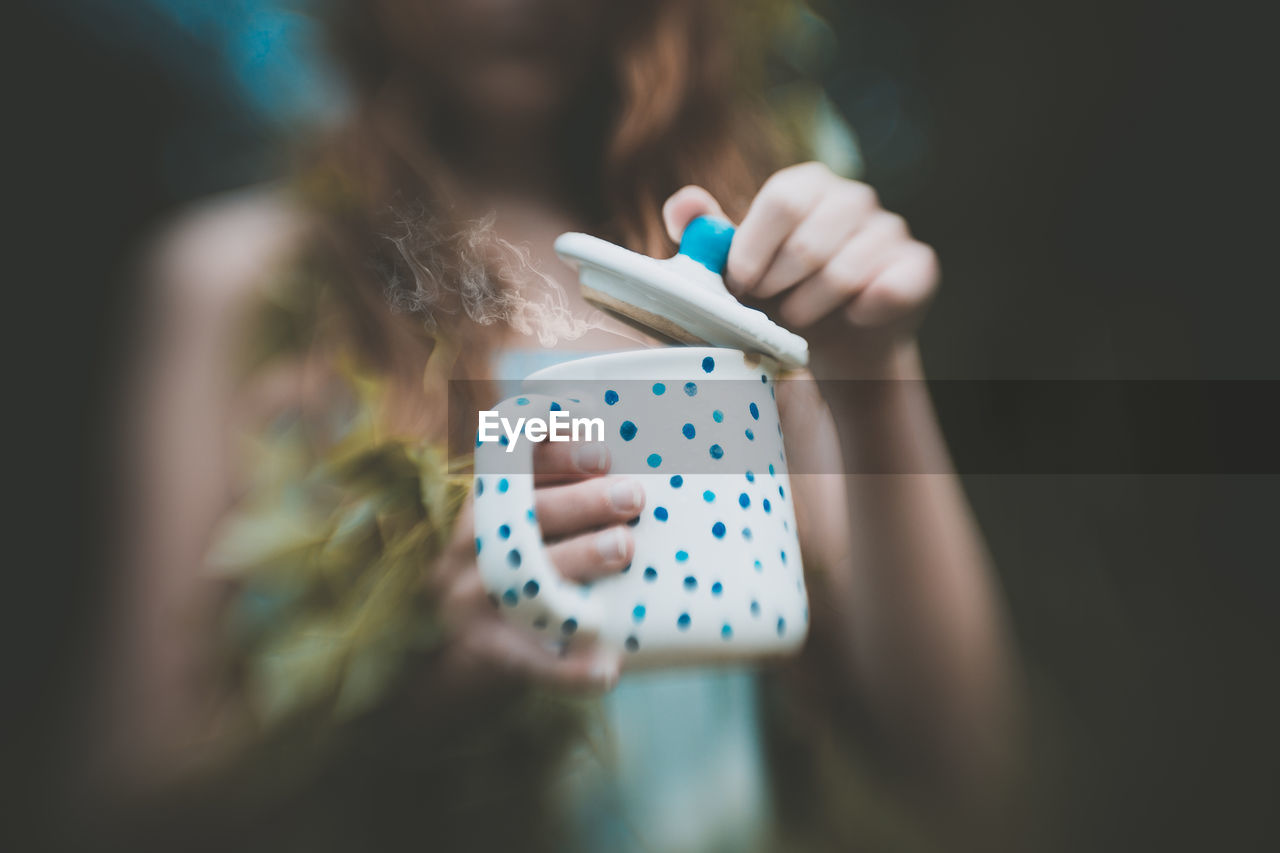 Midsection of woman holding cup with steam