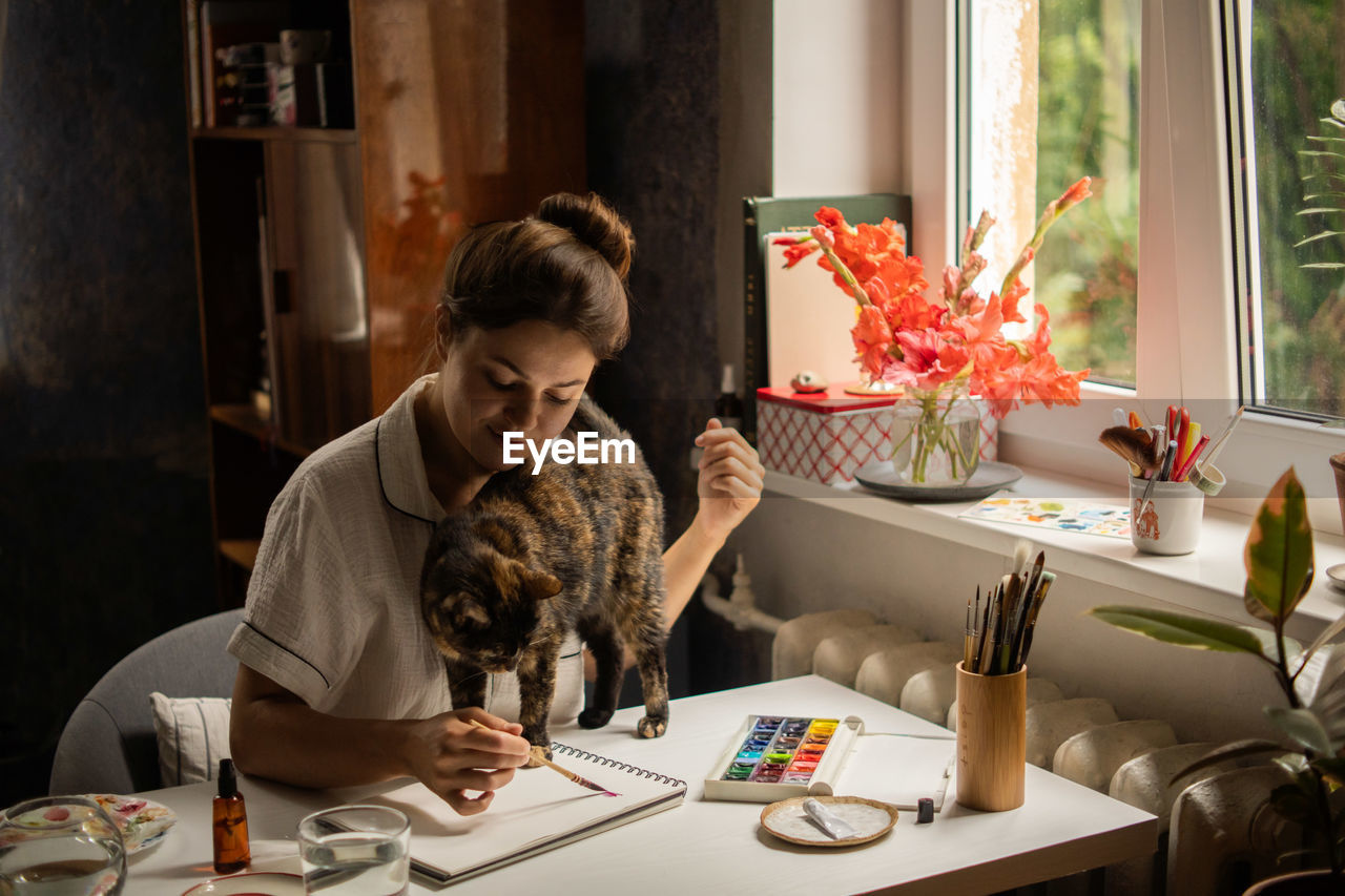 Female painter artist making an abstract watercolor painting. painting with cat