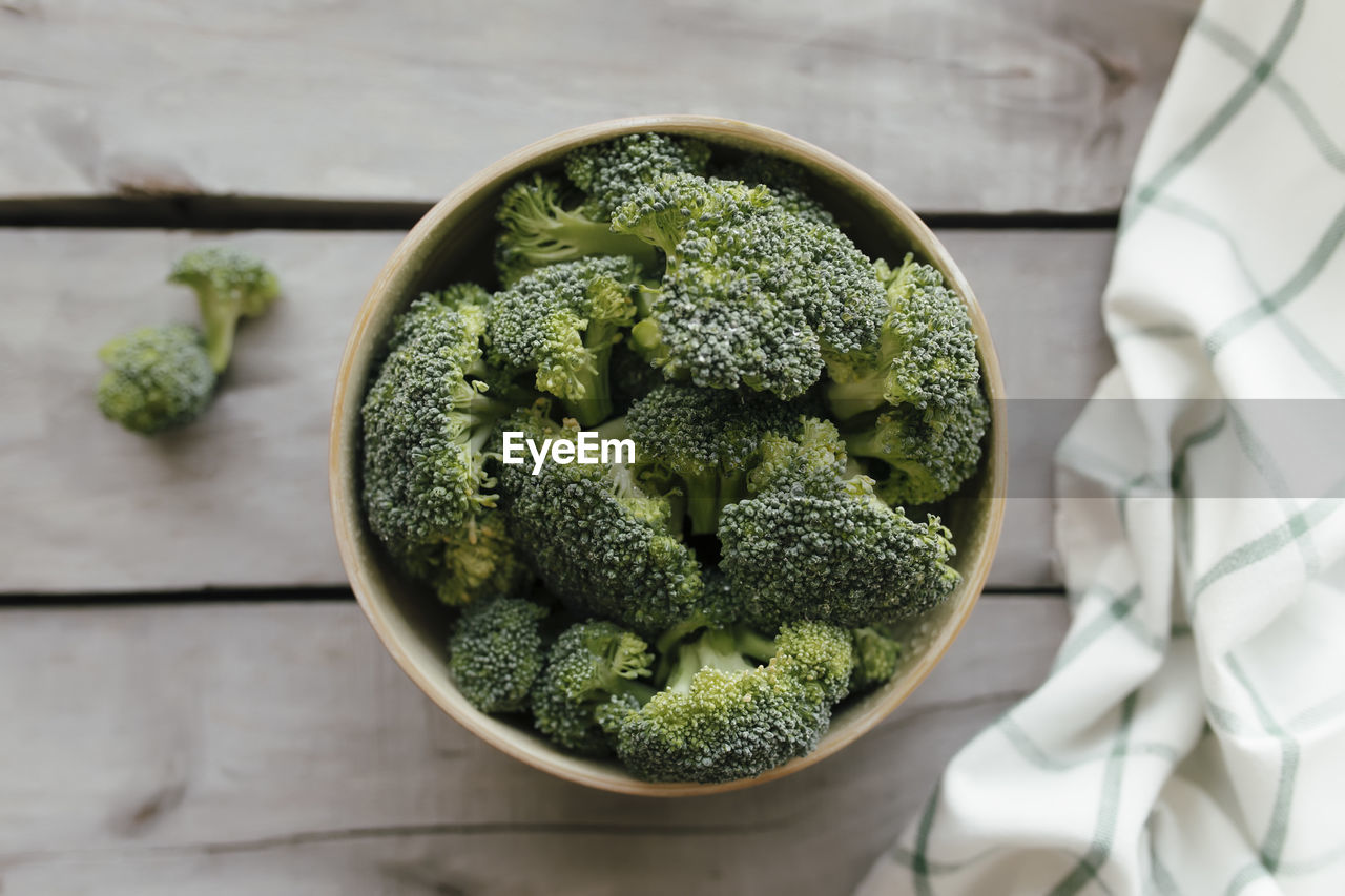 Green fresh broccoli in bowl on wooden background, white towel. healthy eating concept