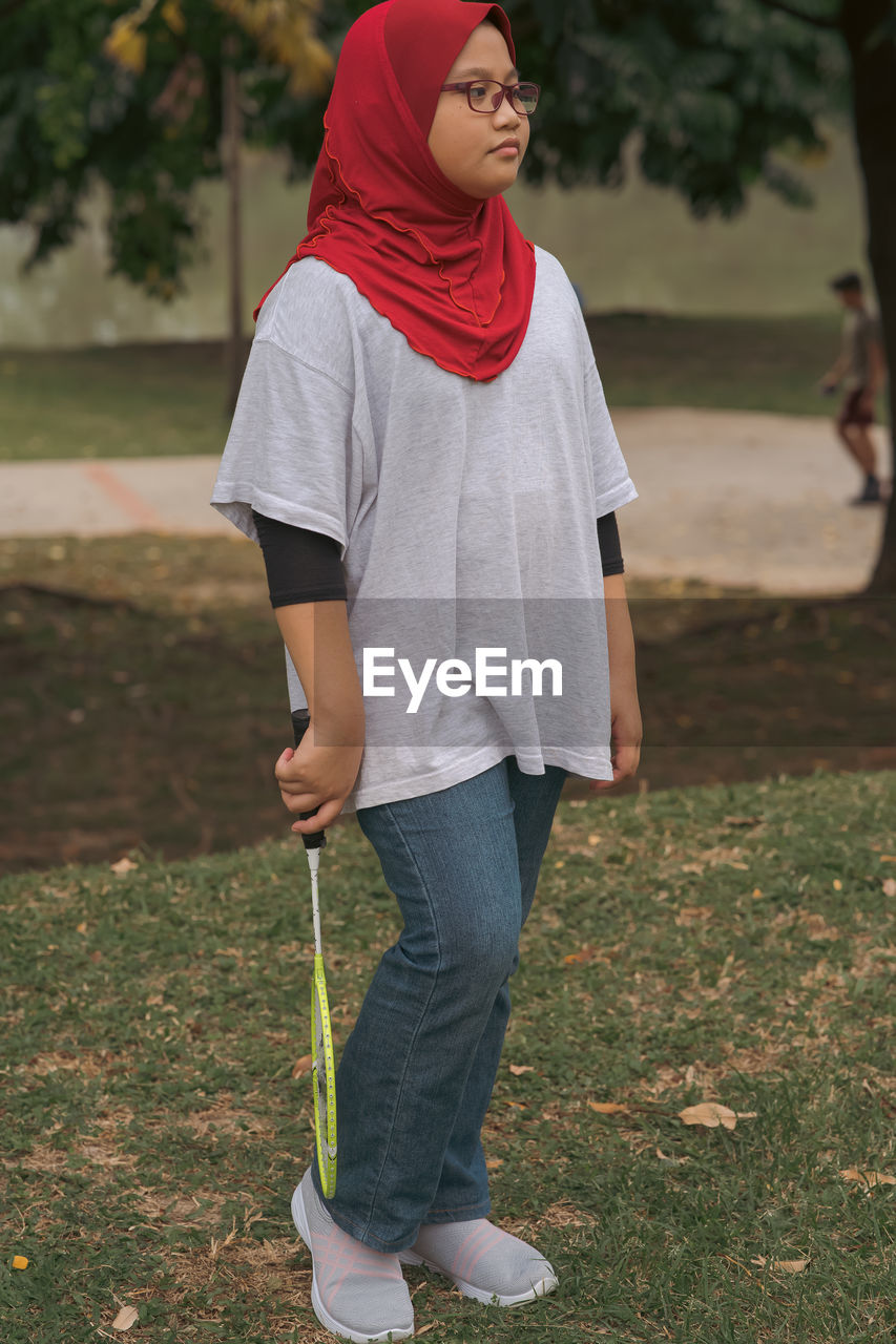 Young hijab asian girl with badminton racket at the park.