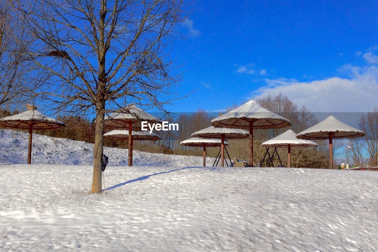 Parasols on snow covered field against sky