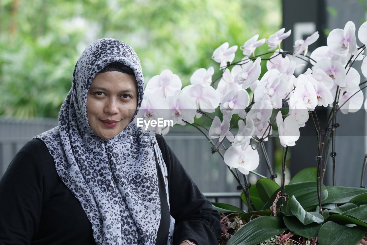 Portrait of woman wearing hijab by flowers