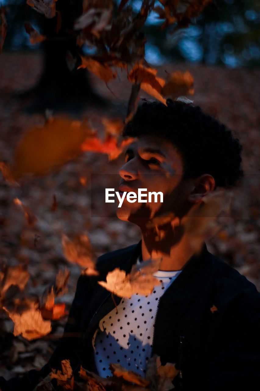 Young man by dry flying leaves at night