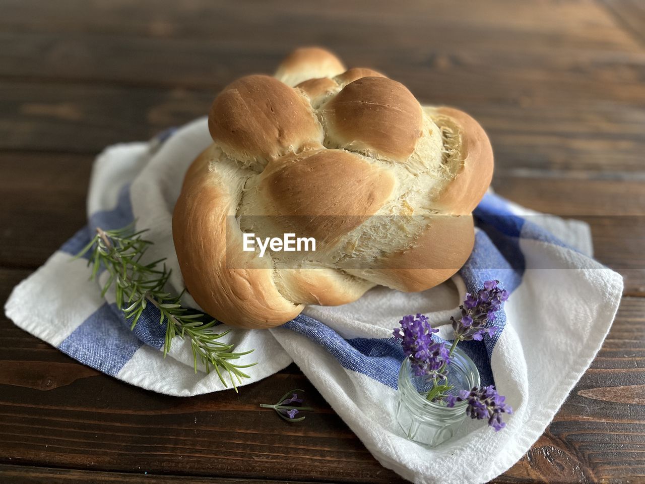 Challah bread on table with towel and herbs