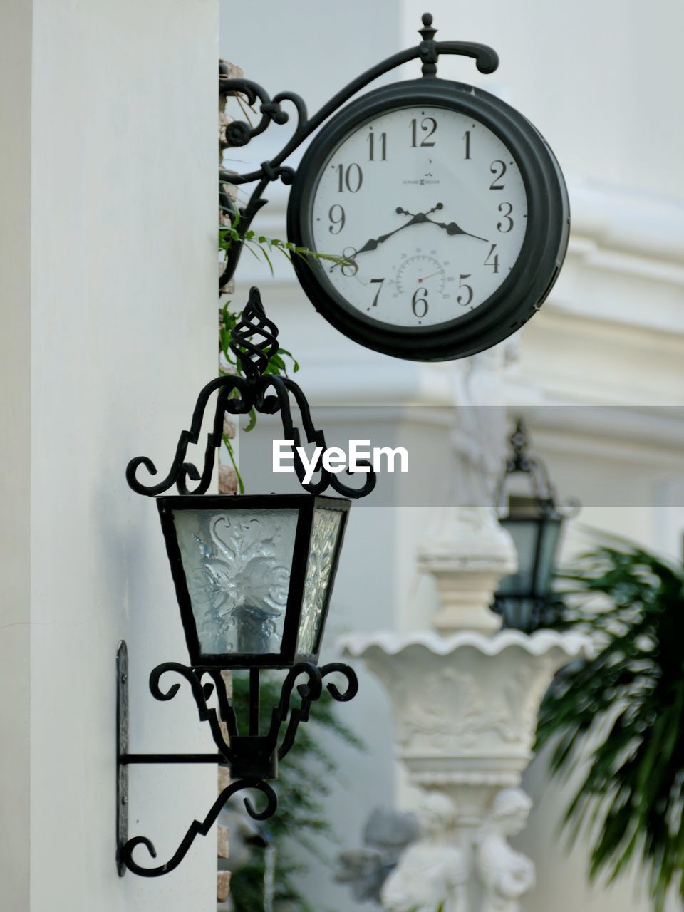 Clock and electric lamp mounted on building wall