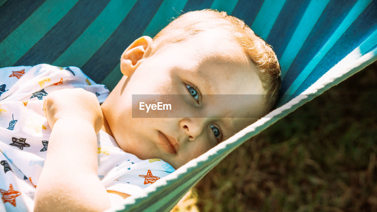 Close-up portrait of cute boy lying outdoors