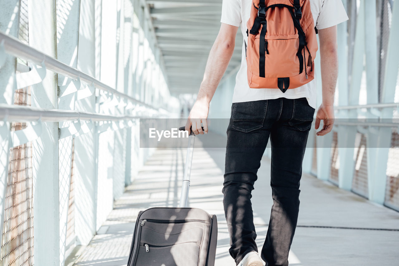 midsection of man with backpack walking on railing