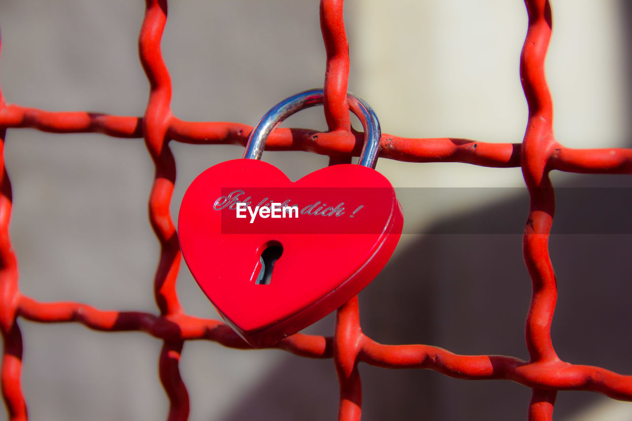 Close-up of red heart shape padlock on metallic fence