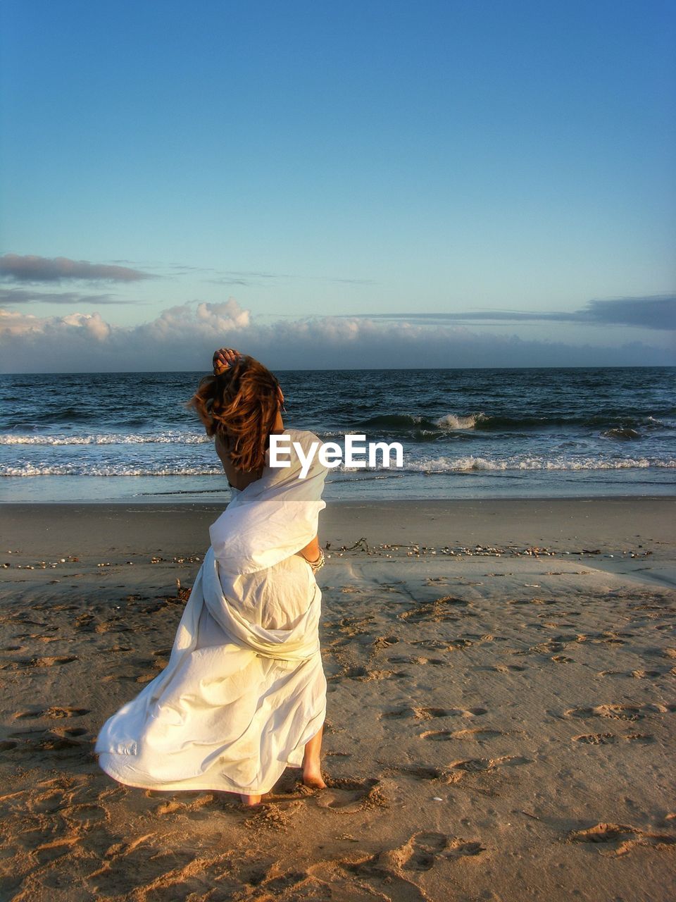 REAR VIEW OF WOMAN ON BEACH AGAINST SEA