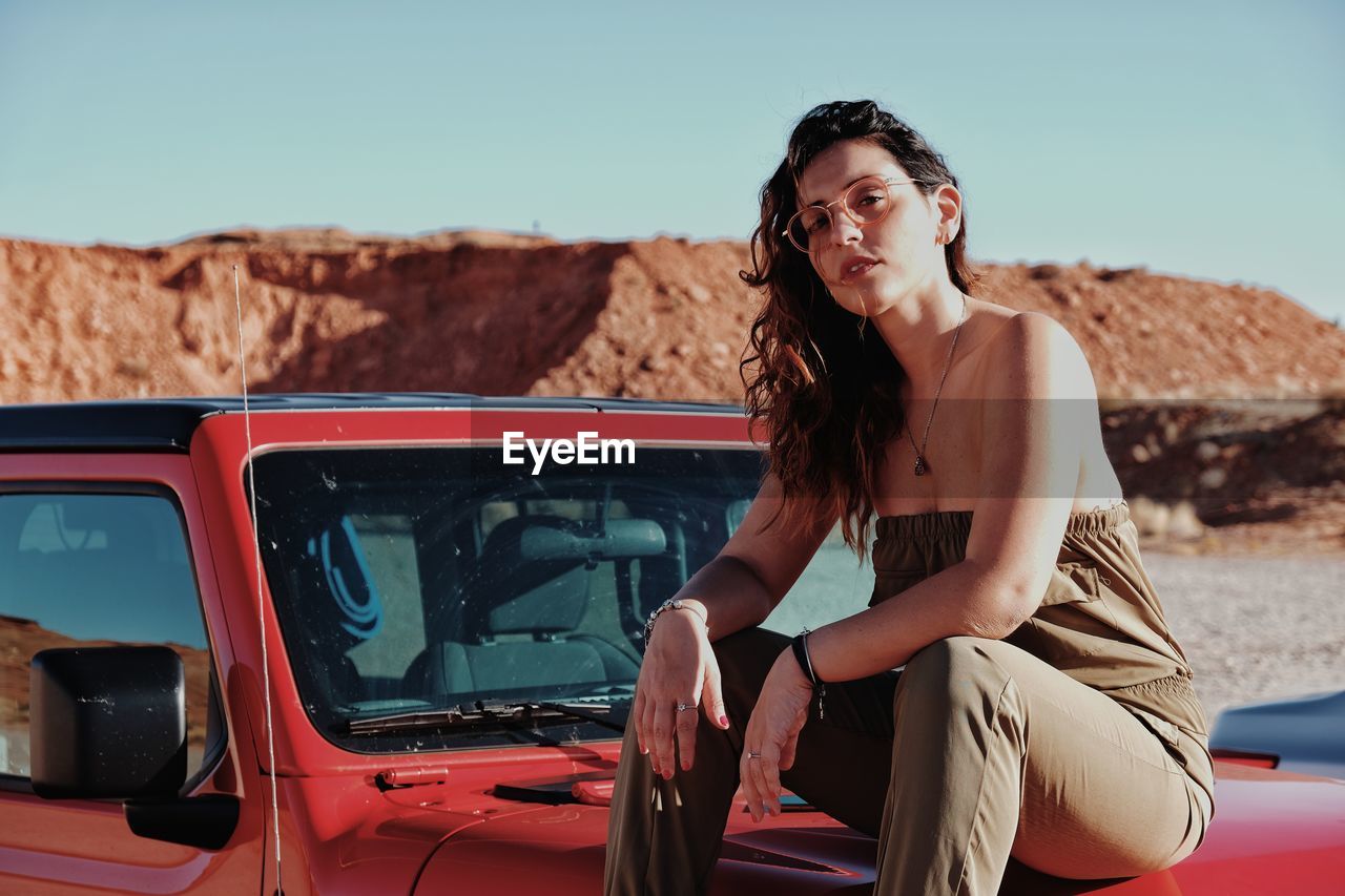 Portrait of beautiful woman in car against sky