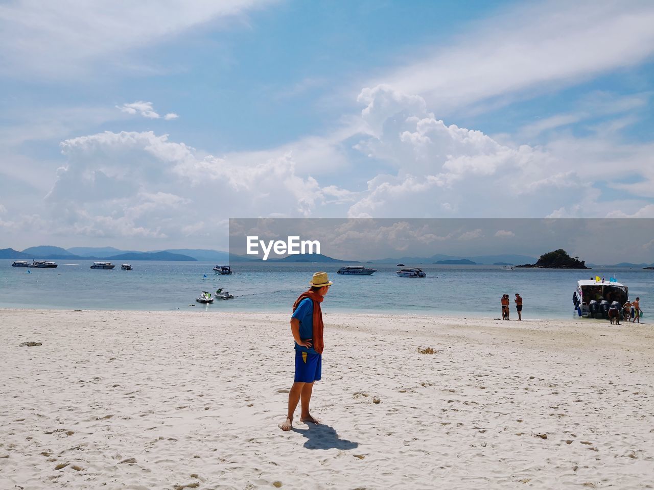 Full length of man standing at beach against cloudy sky