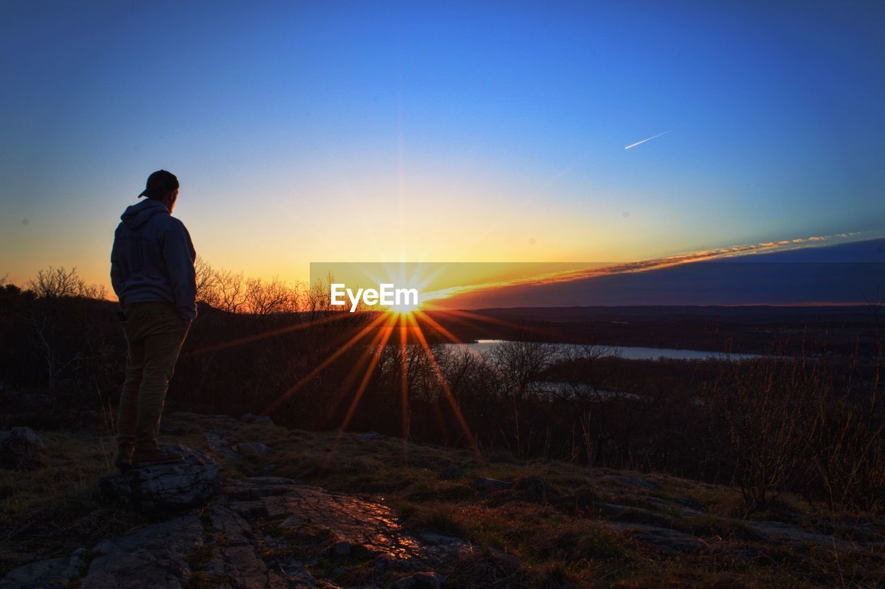 Full length of man on hill standing against blue sky during sunset