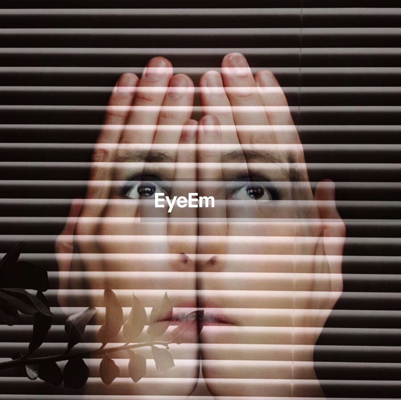 Double exposure of woman face with hands against blinds