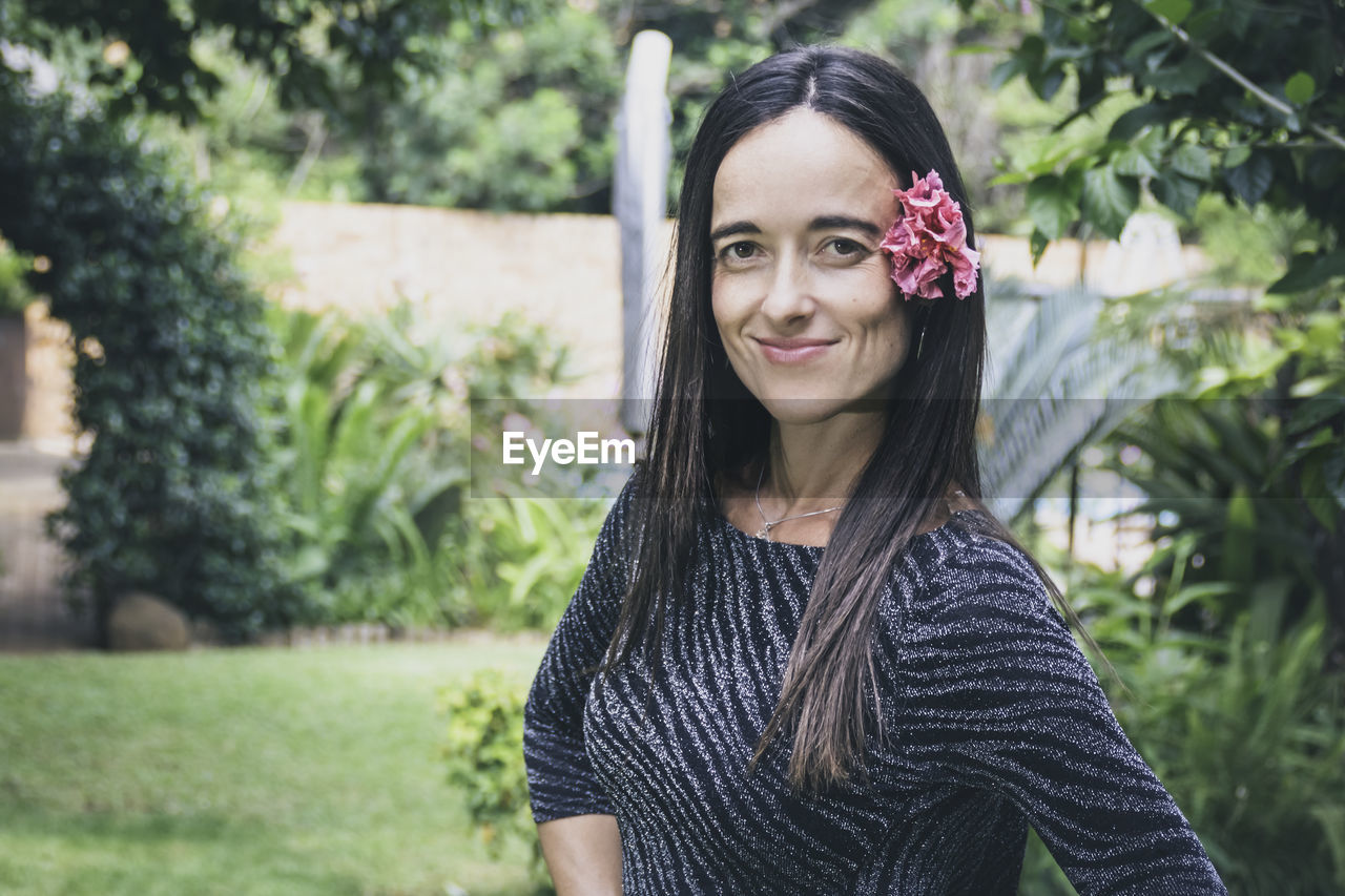 Beautiful woman with flower in her hair standing in her garden.