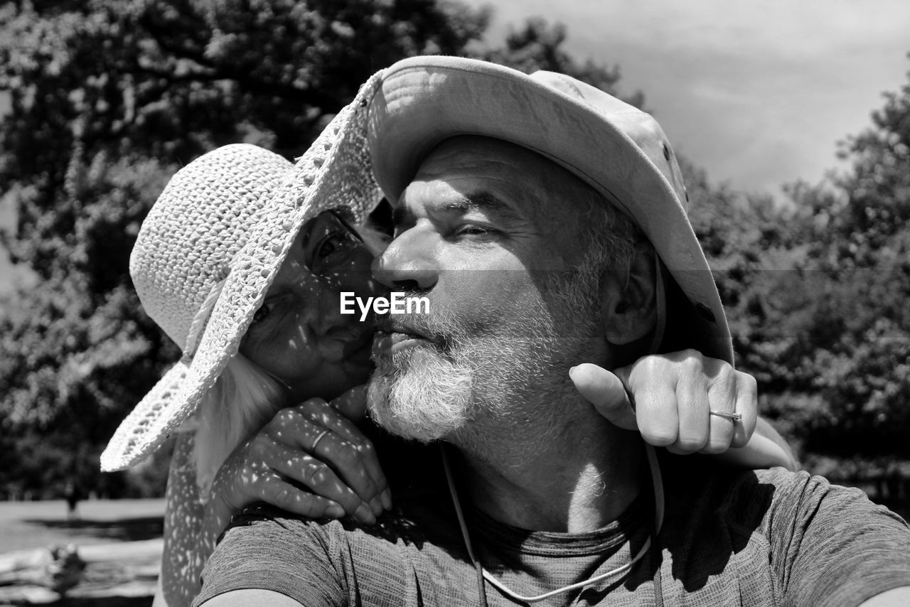 Couple wearing hat embracing while standing outdoors