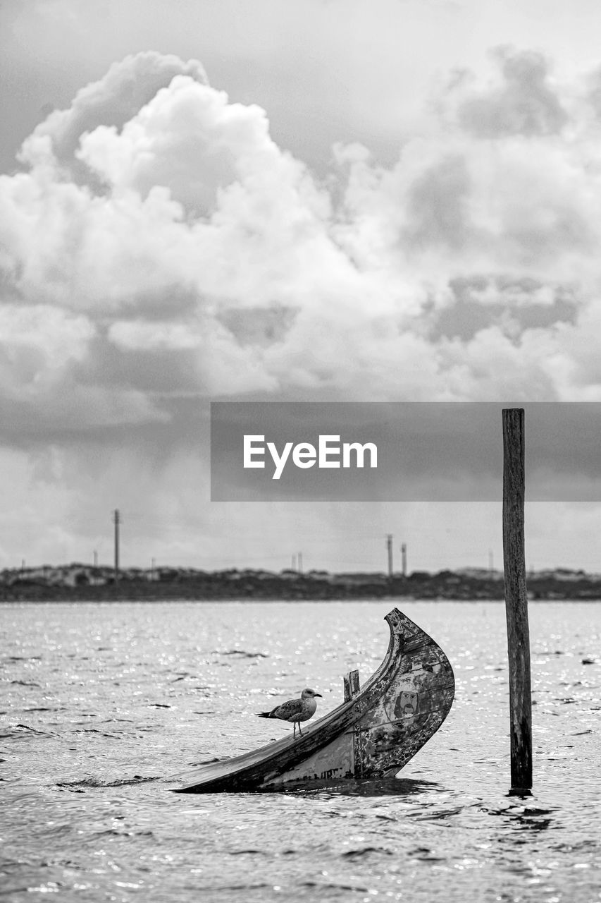 Old ship post in sea against sky