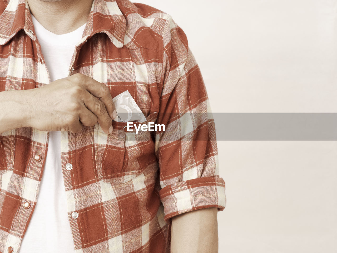 CLOSE-UP OF HAND HOLDING UMBRELLA OVER WHITE BACKGROUND