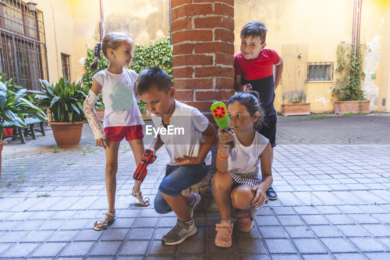 Group of little boys of different ages having fun and playing together in a courtyard