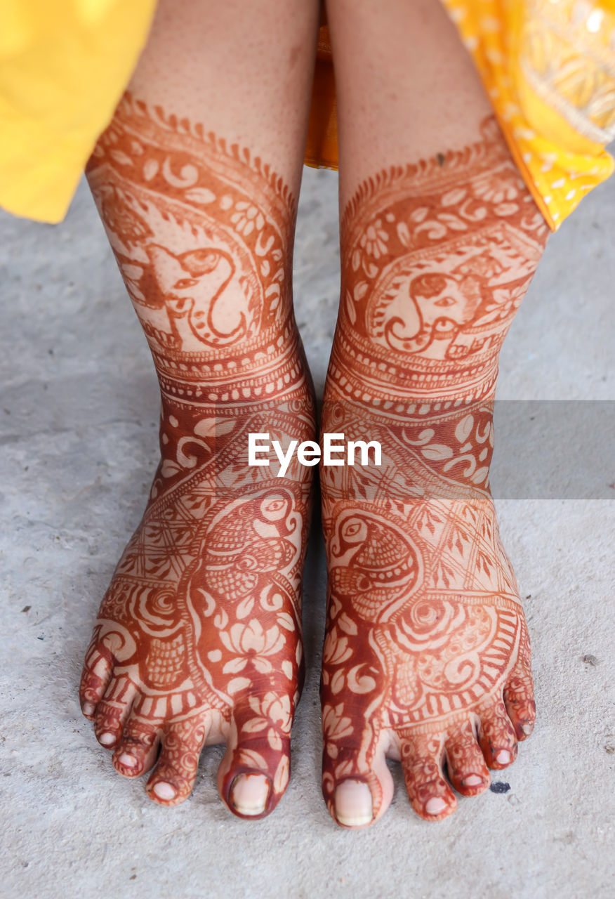 Feet decorated with amazing henna tattoo or mehndi art from flat angle