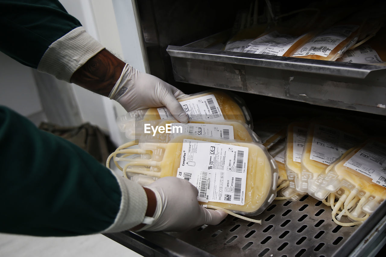 Cropped hands of doctor keeping blood bags in tray