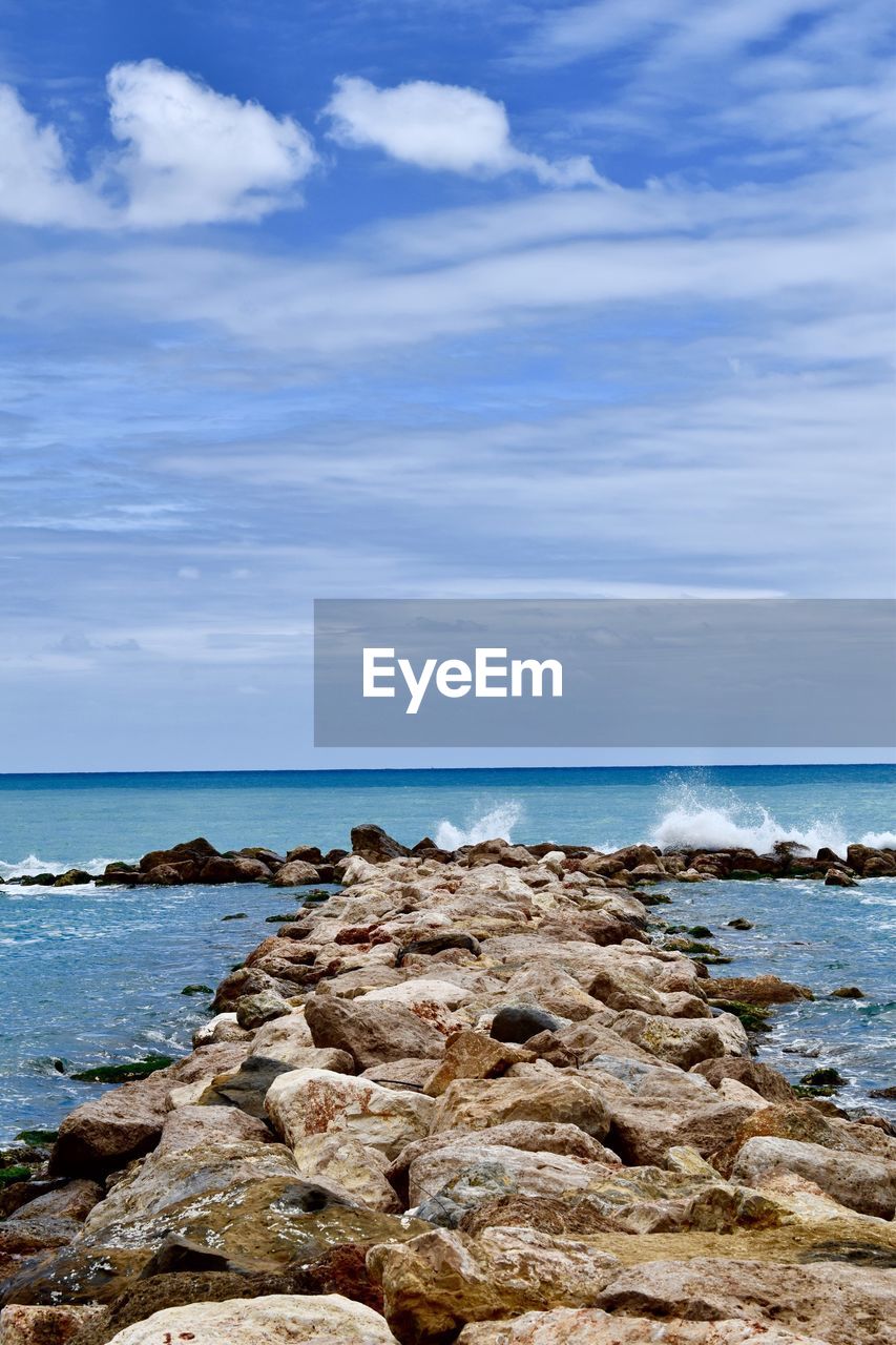 ROCKS ON SHORE AGAINST SKY