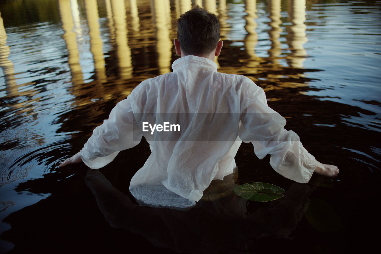 Rear view of man standing in lake