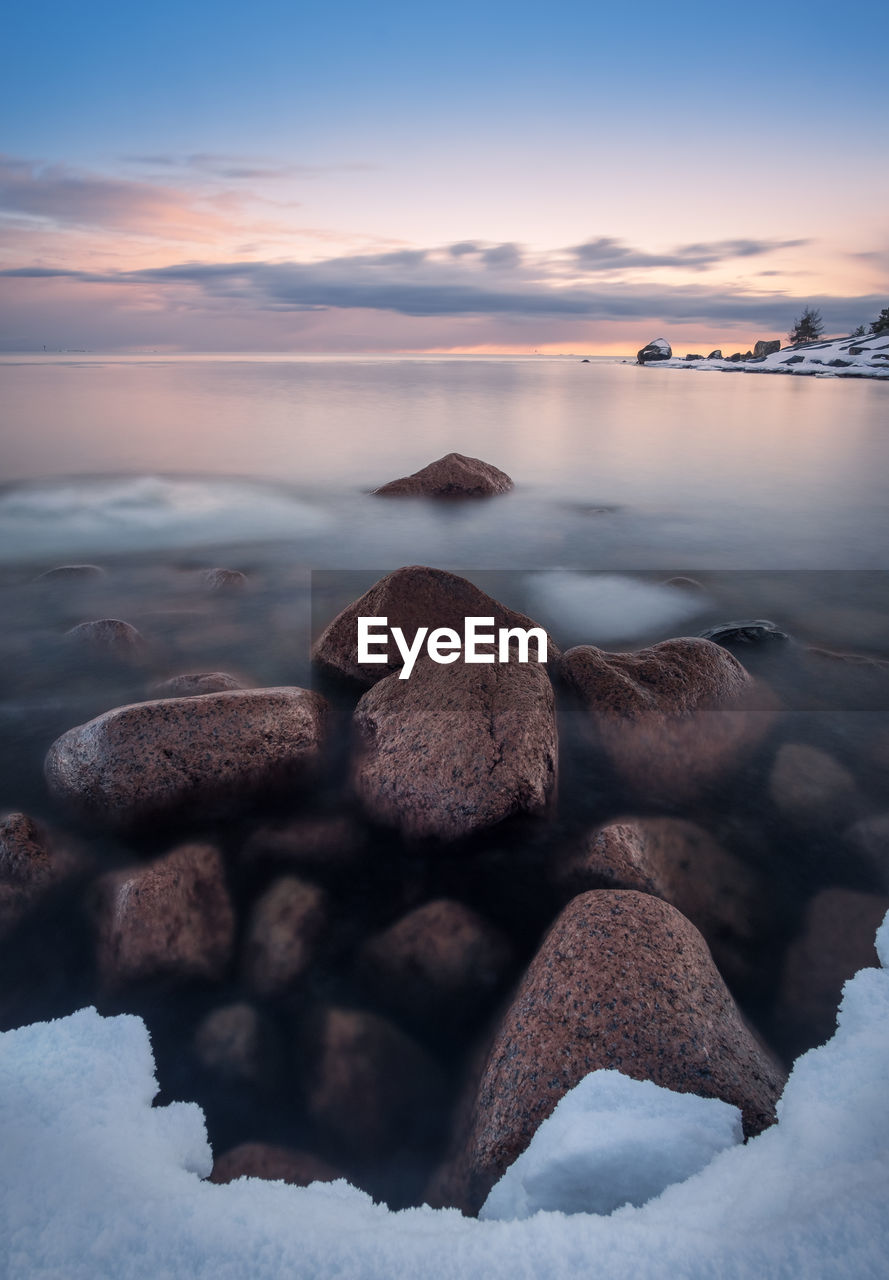 Rocks in sea during sunset