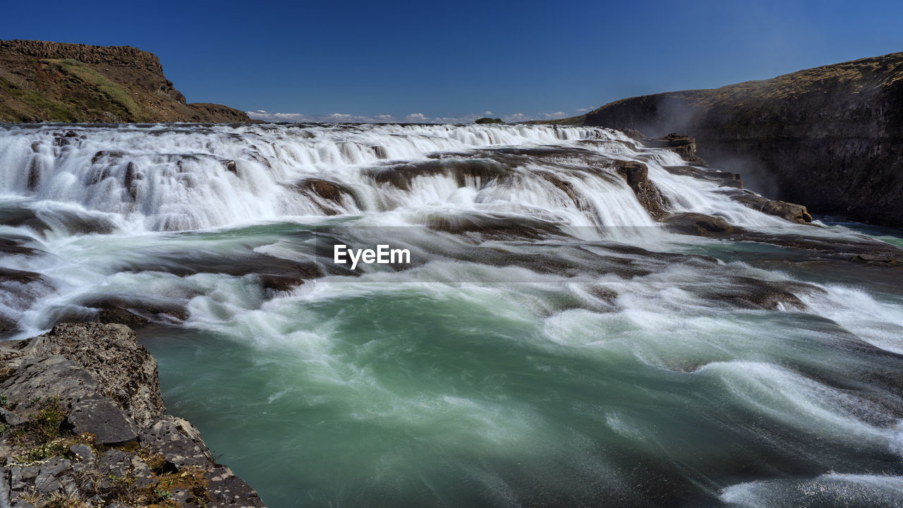 Scenic view of waterfall against sky
