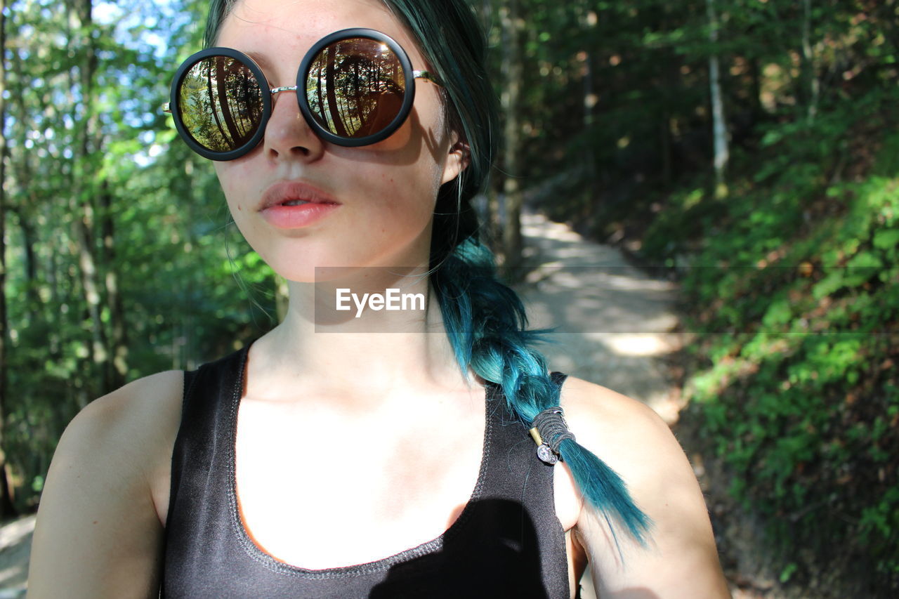 Close-up portrait of woman in sunglasses against trees