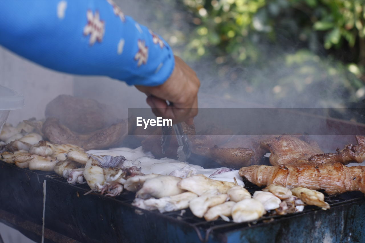 Person preparing food on barbecue grill