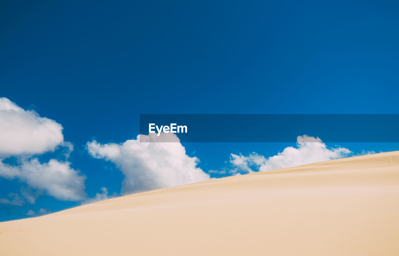 Low angle view of desert against blue sky