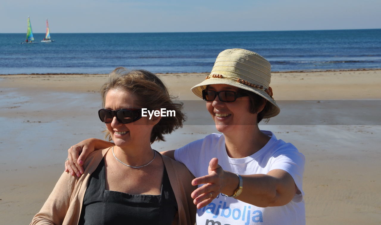 Female friends enjoying at beach on sunny day