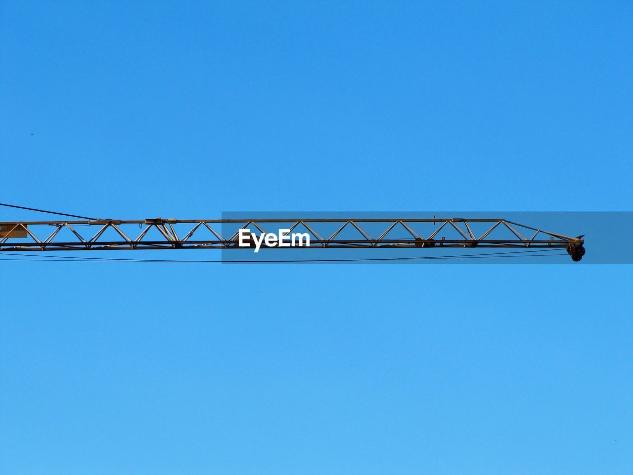 Low angle view of crane against clear blue sky