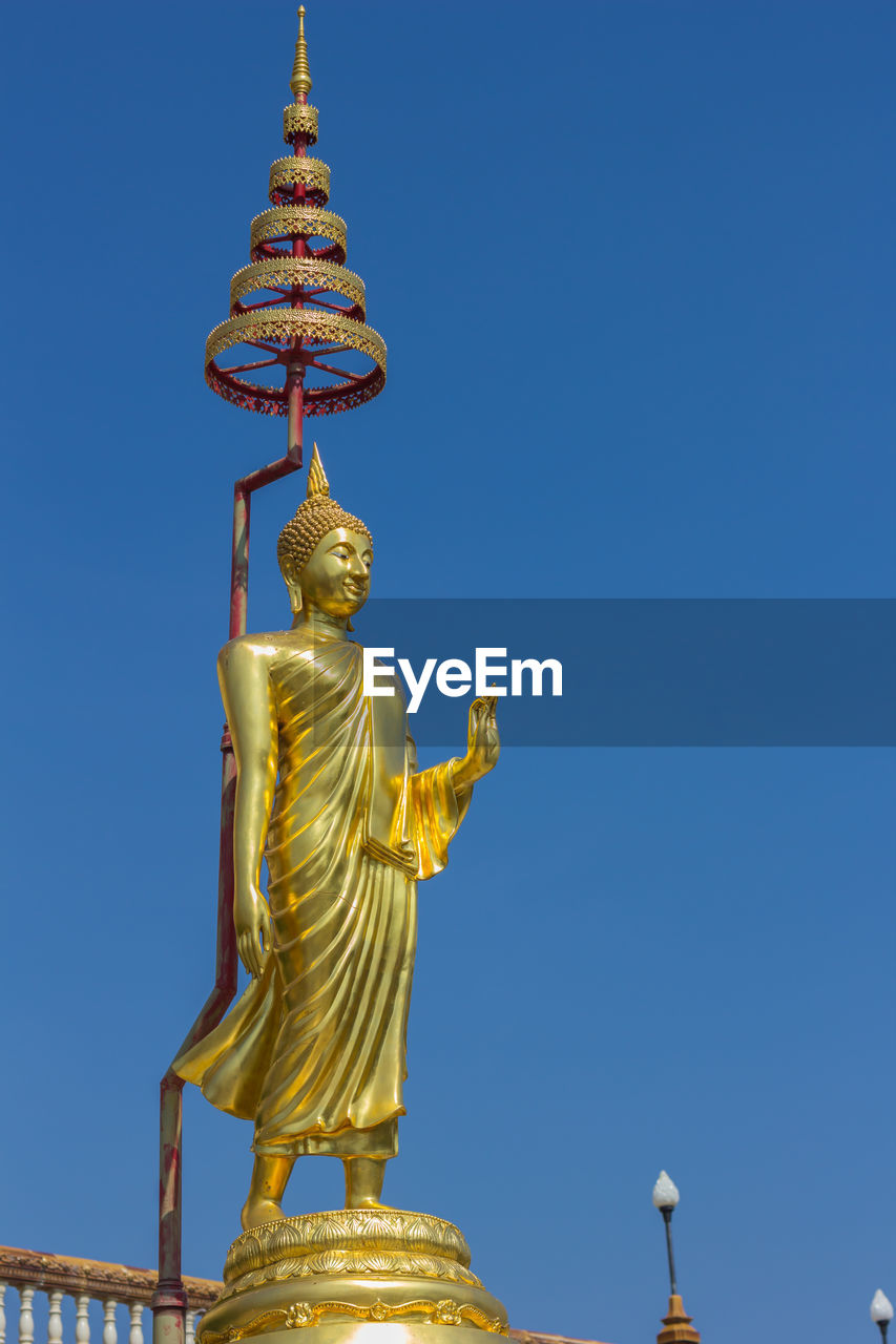 Low angle view of statue against temple against clear blue sky