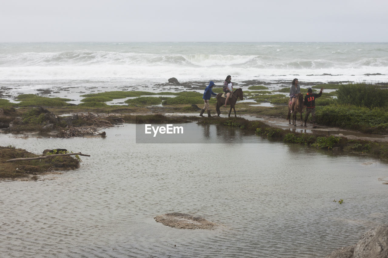 MEN WORKING AT BEACH AGAINST SKY