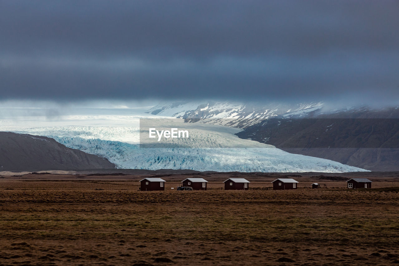 5 cabins with a scenic view of an icelandic glacier in the background with low clouds