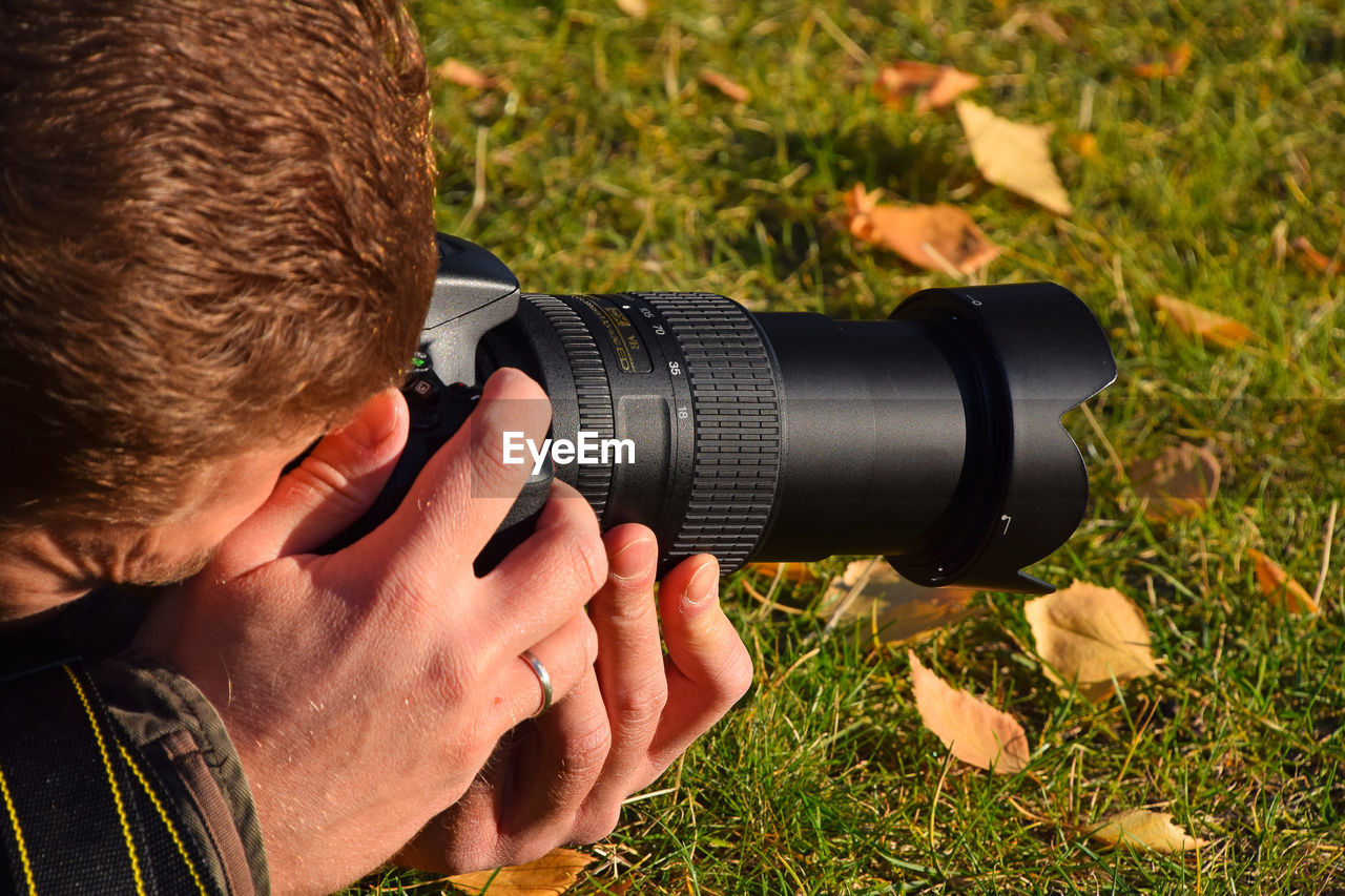 Cropped image of man photographing on field during autumn