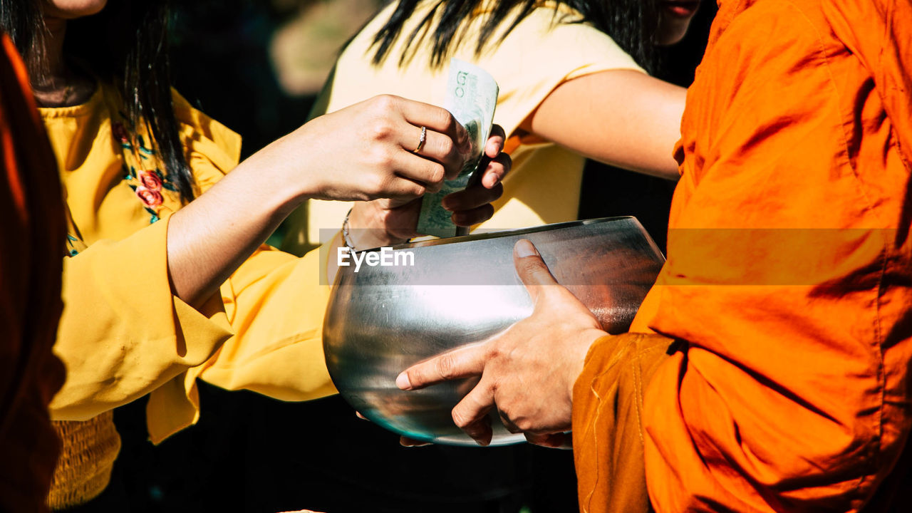 Midsection of woman giving money to monk