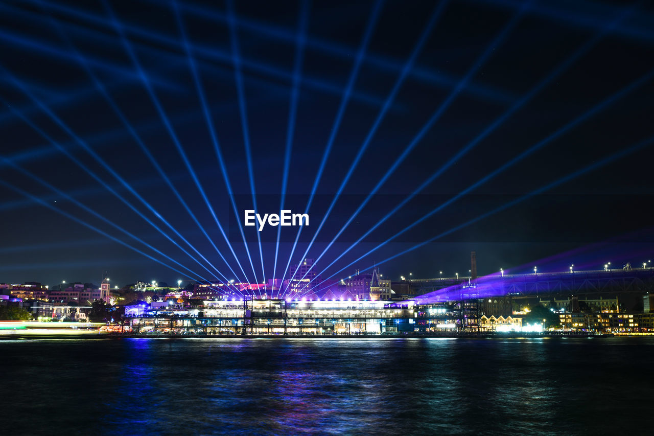 ILLUMINATED BRIDGE OVER RIVER AT NIGHT