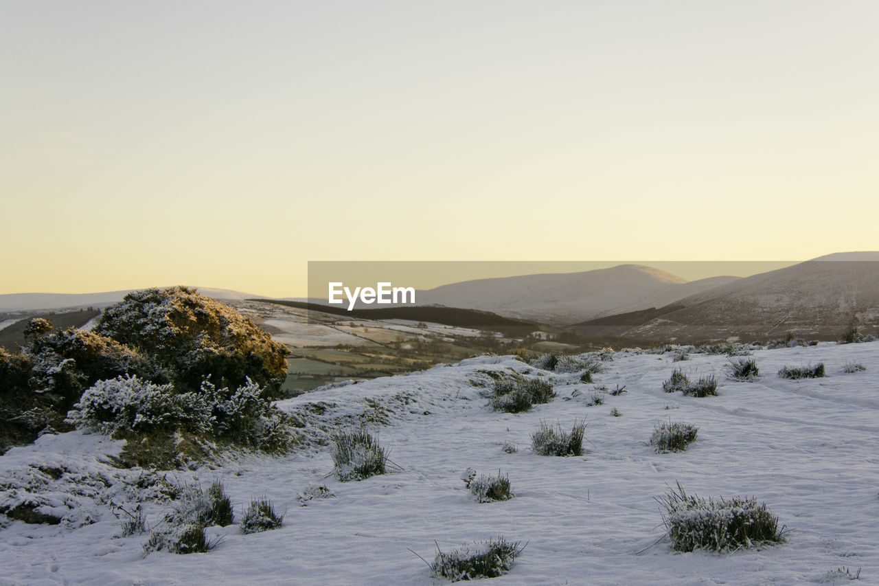 Scenic view of upland landscape against clear early morning sky during winter