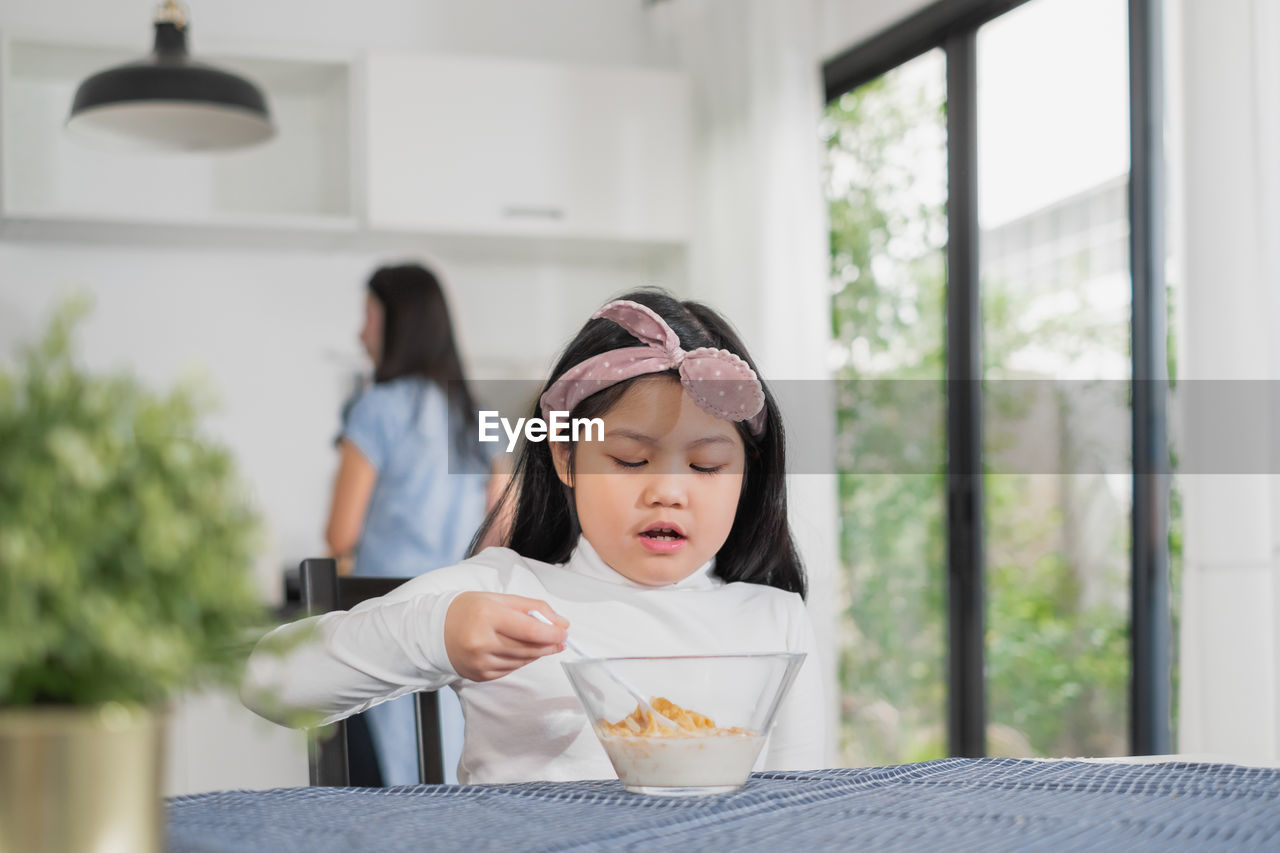 Girl eating breakfast on table at home