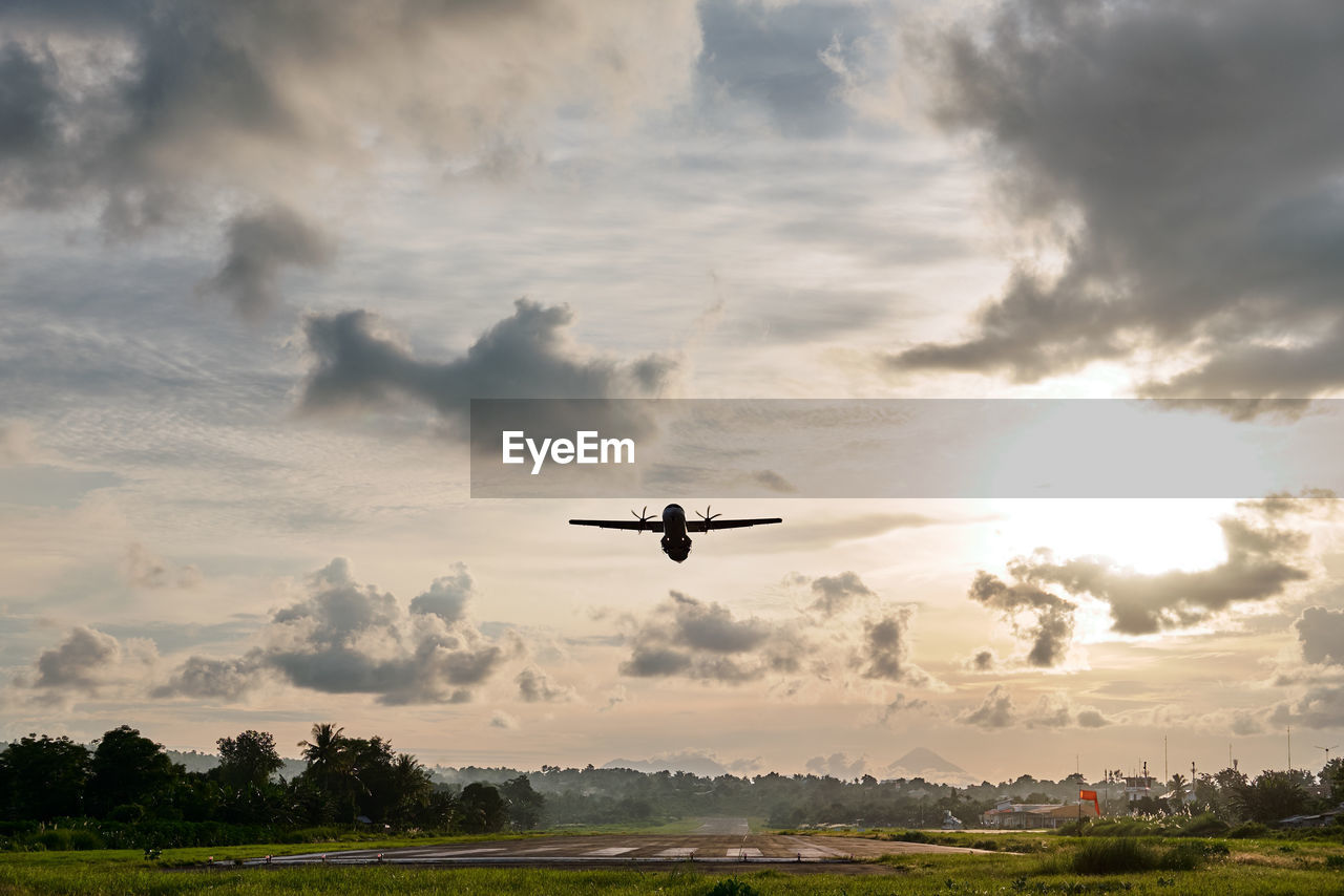 Airplane flying in sky during sunset