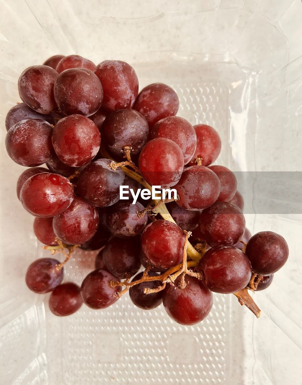 Grapes in a translucent plastic punnet. one bunch. red grapes, fresh and juicy.