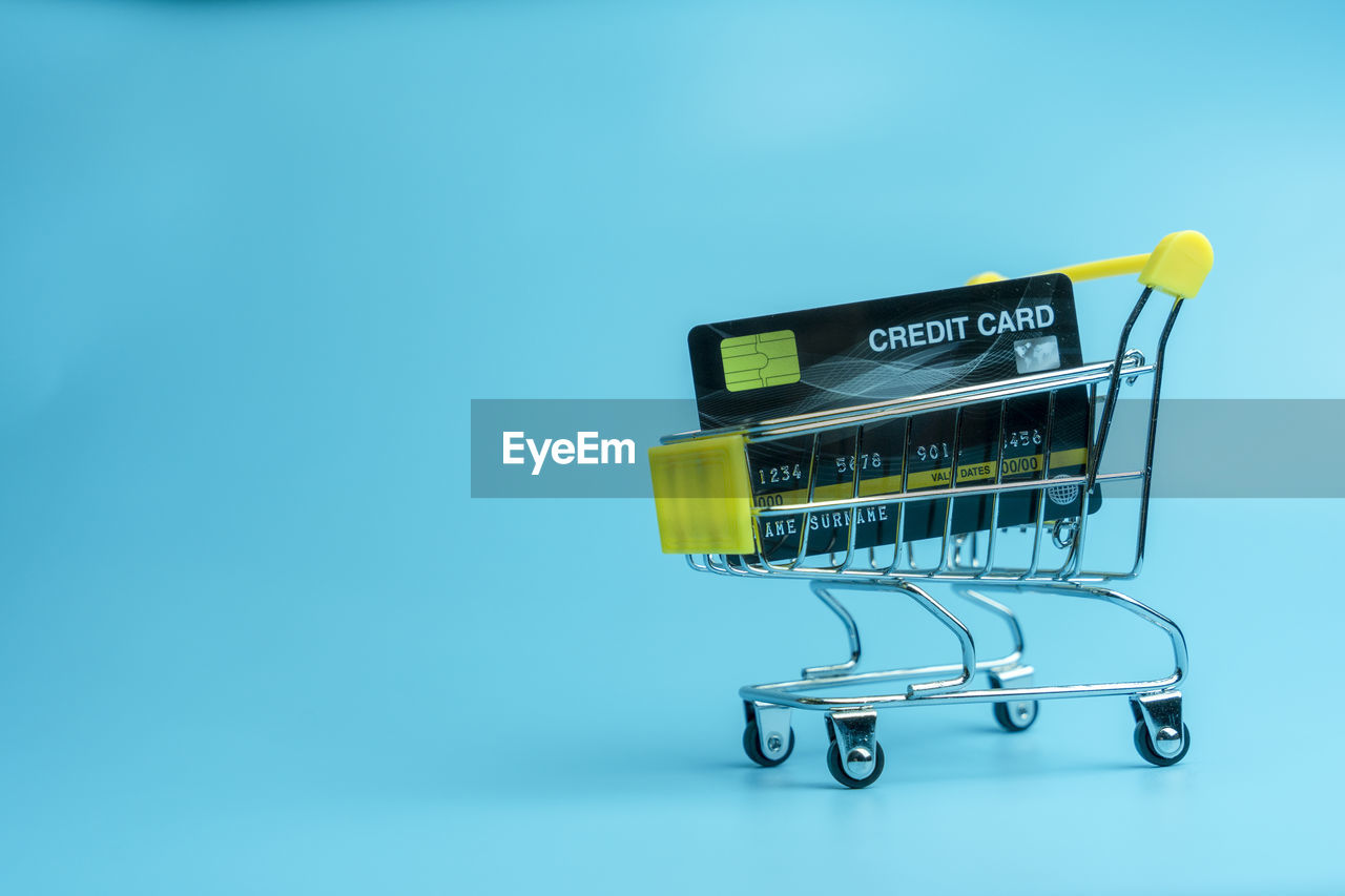 Close-up of shopping cart on blue background