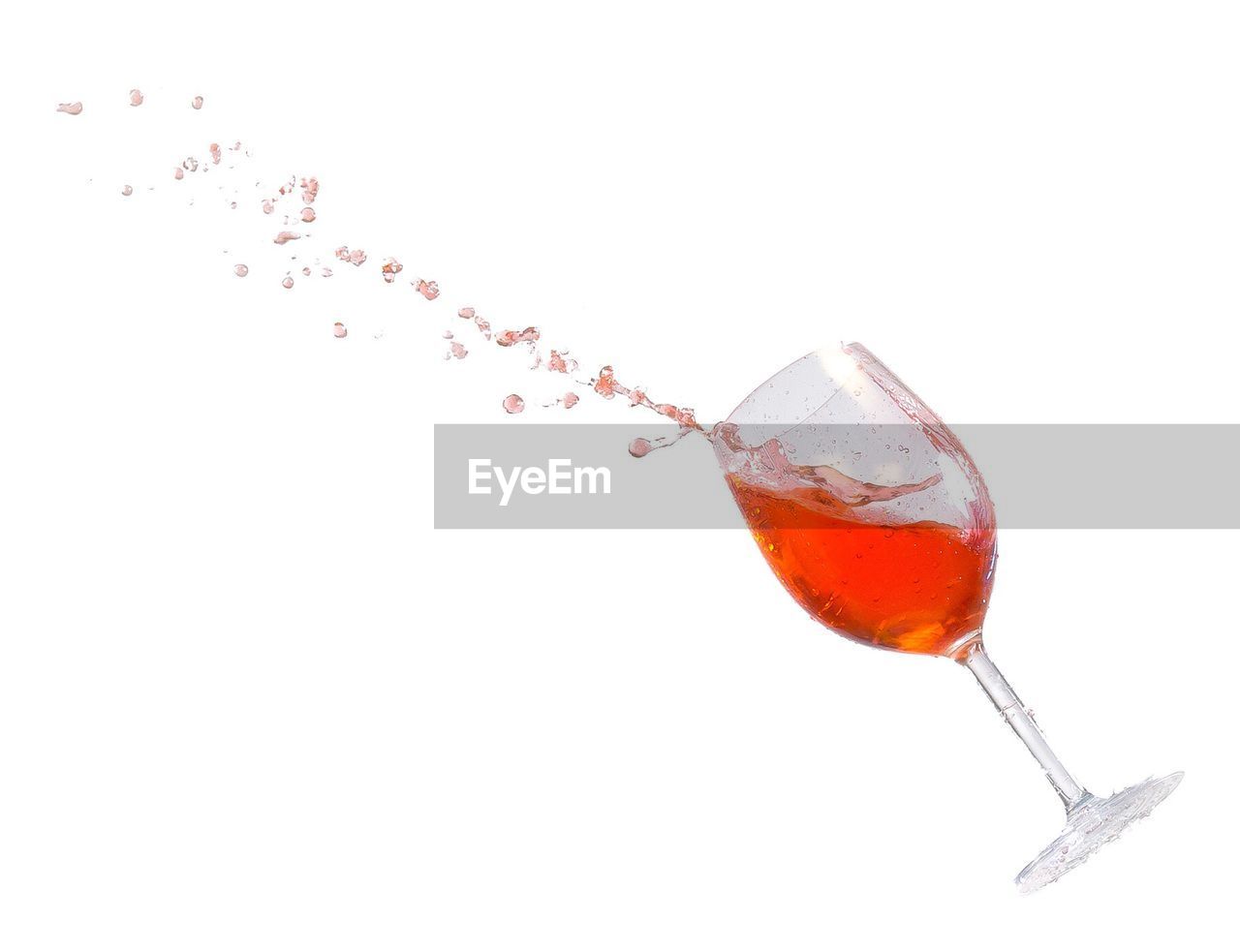 Wine splashing in glass against white background