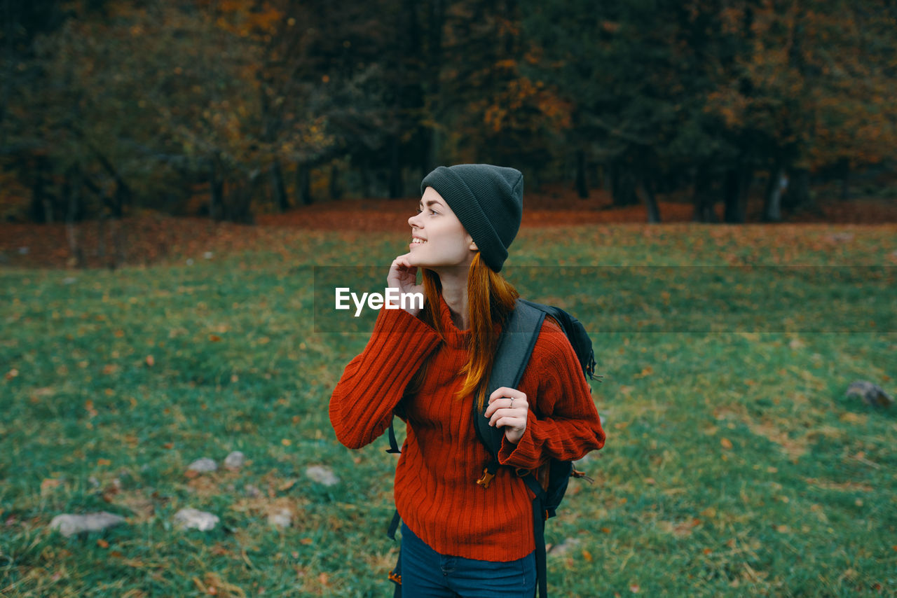 BEAUTIFUL YOUNG WOMAN LOOKING AWAY ON FIELD