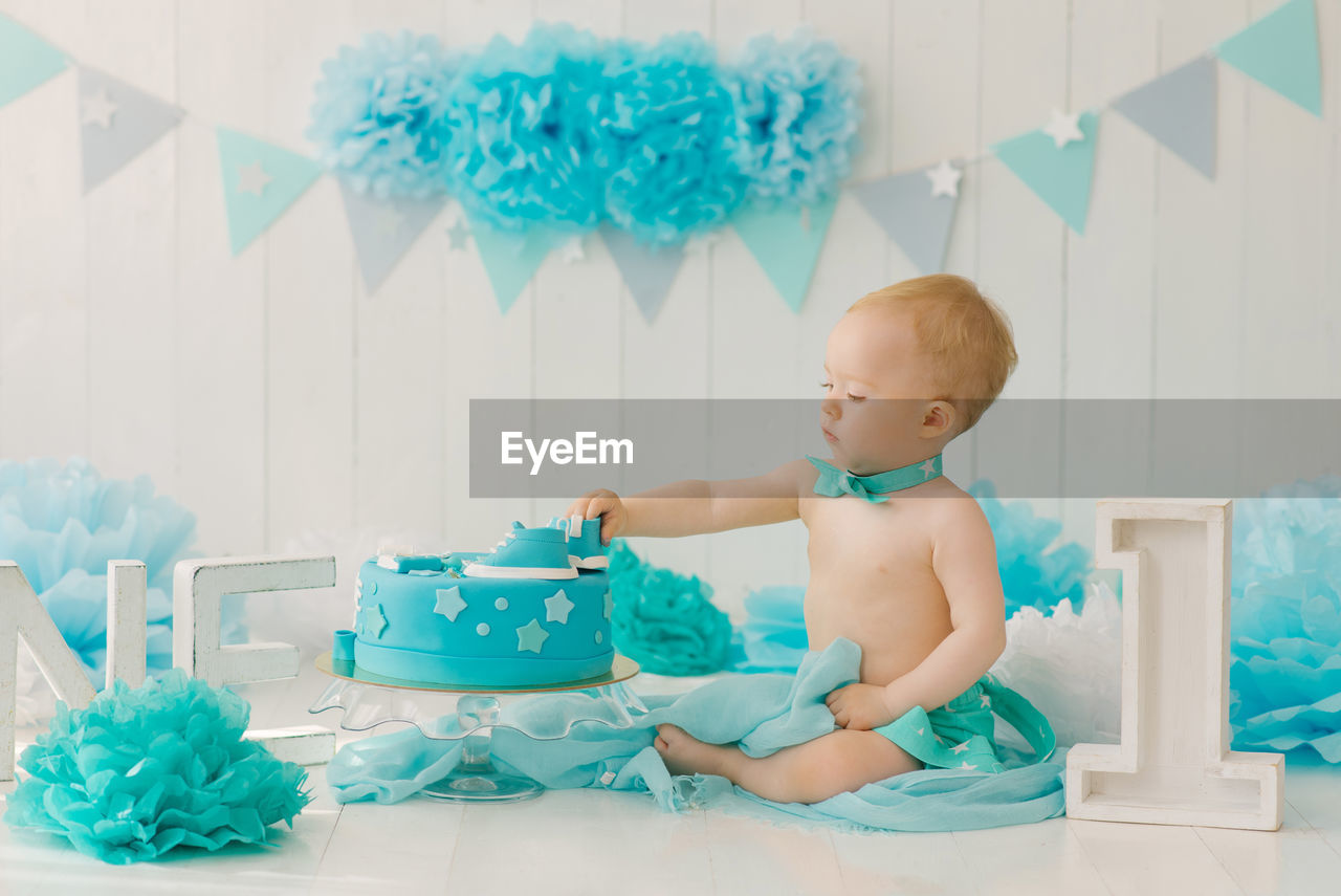 Birthday party for a one-year-old boy in blue and turquoise garlands and a cake, holiday concept
