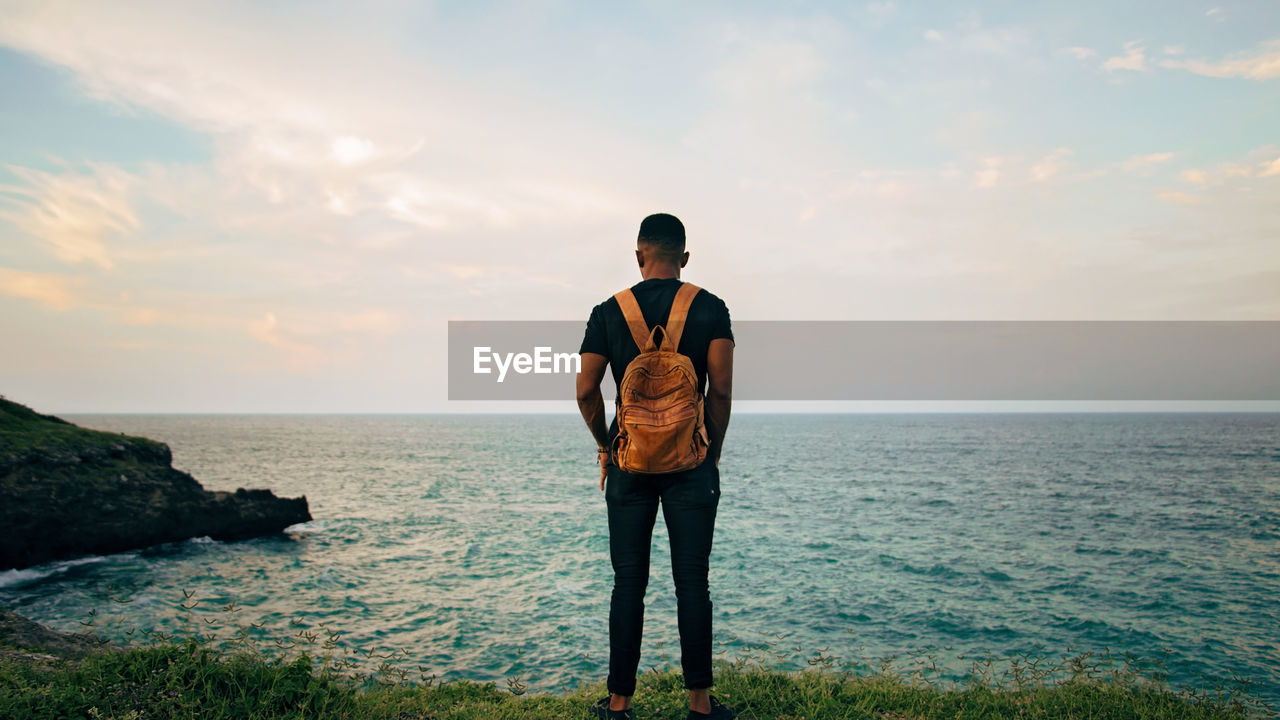 Rear view of man looking at sea against sky